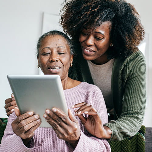 An older Black woman and her daughter are looking at a tablet. An older Black woman and her daughter are looking at a tablet.