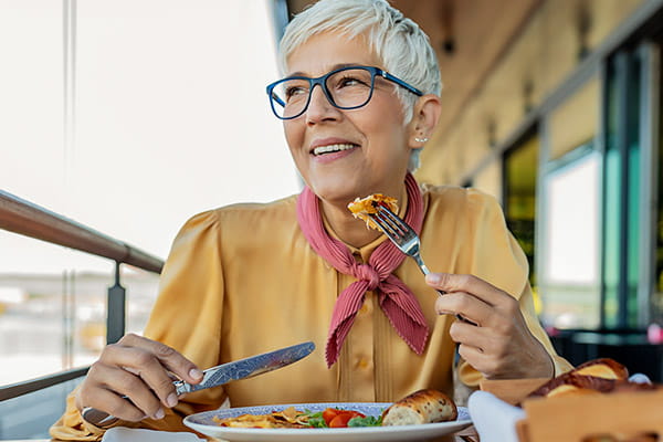 A senior woman is smiling while eating a balanced meal. A senior woman is smiling while eating a balanced meal.